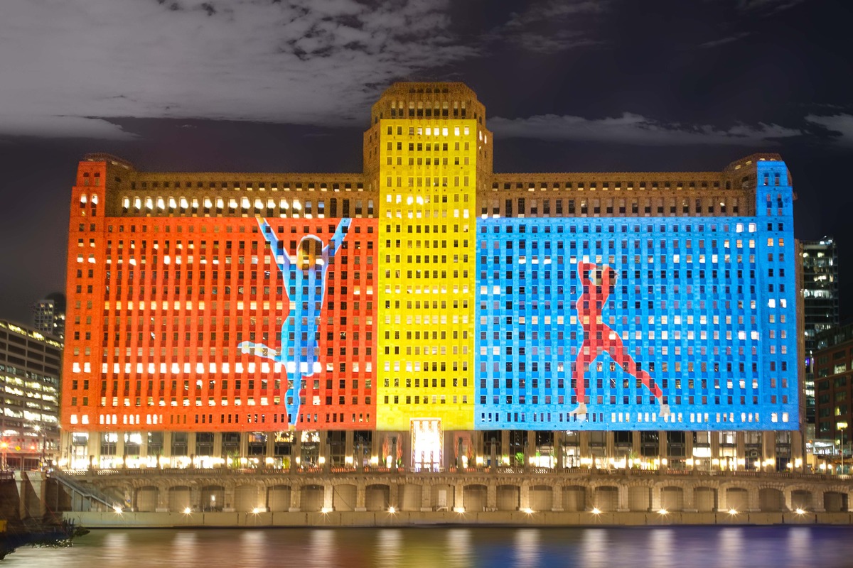 A projection on a large building shows two dancers set against blocks of primary color