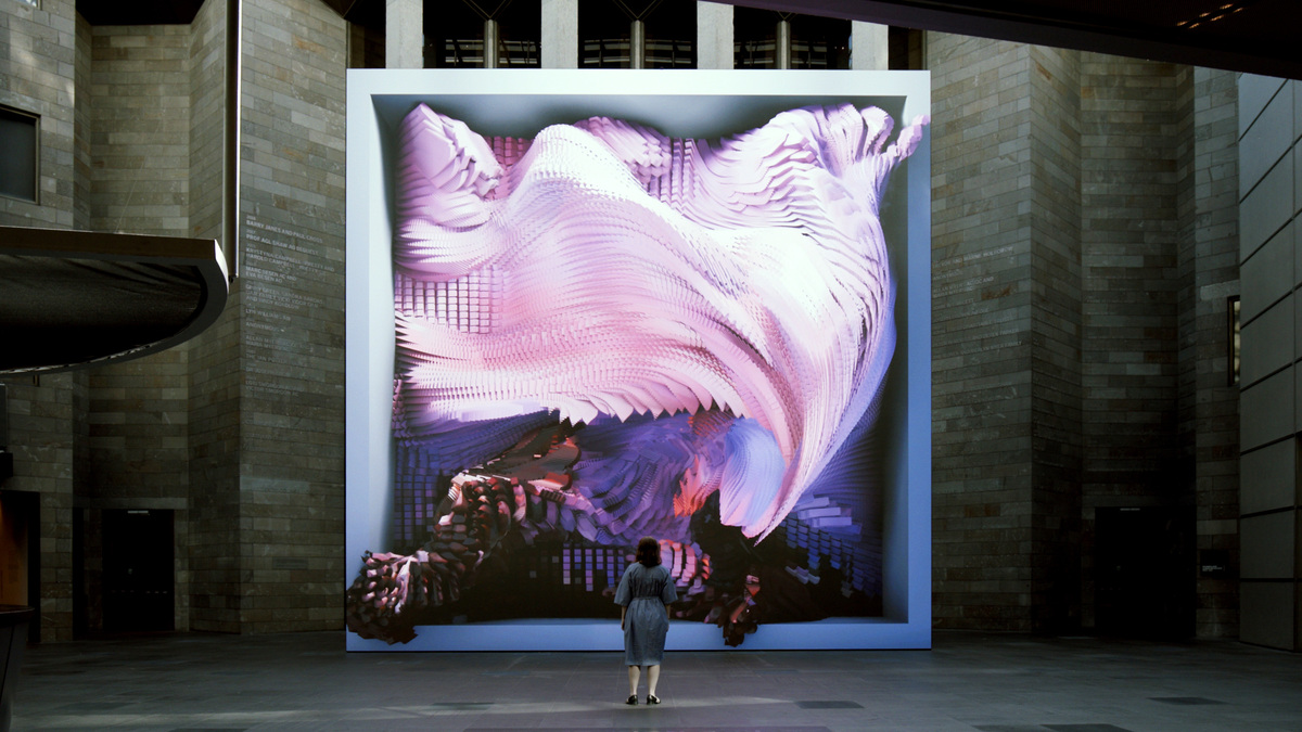 A large square screen with an abstract purple image seeming to pour out of it, with a woman in a blue dress standing in front of it