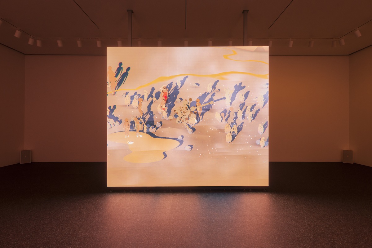 A photo of a gallery bathed in a pale orange light, with a large square screen showing a digitally rendered desert-like landscape