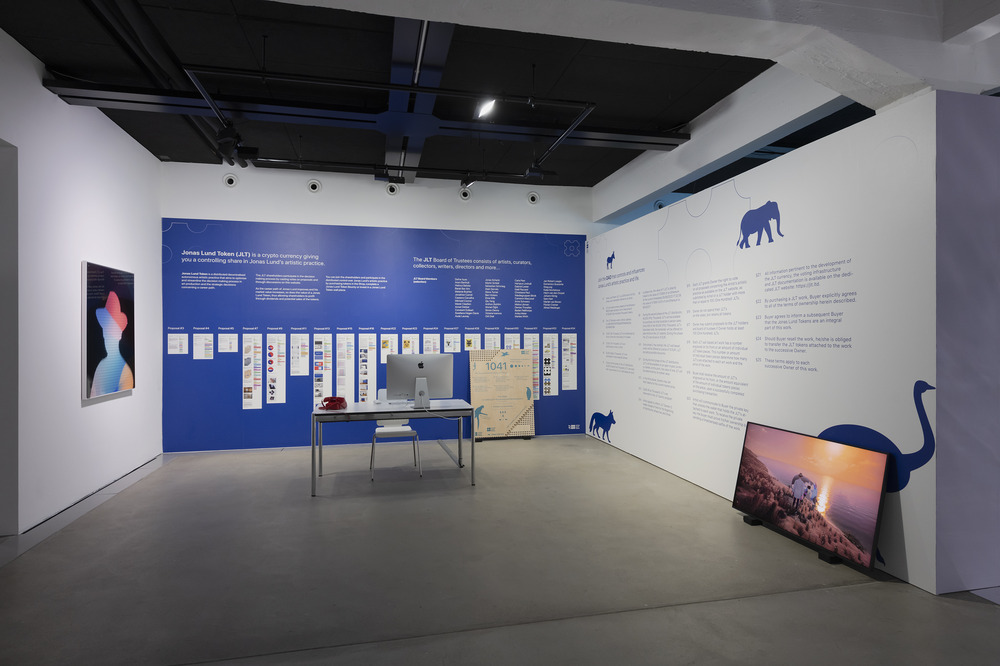 A gallery features abundant text on its two walls, along with charts. The office-like environment also includes a computer and phone on a desk