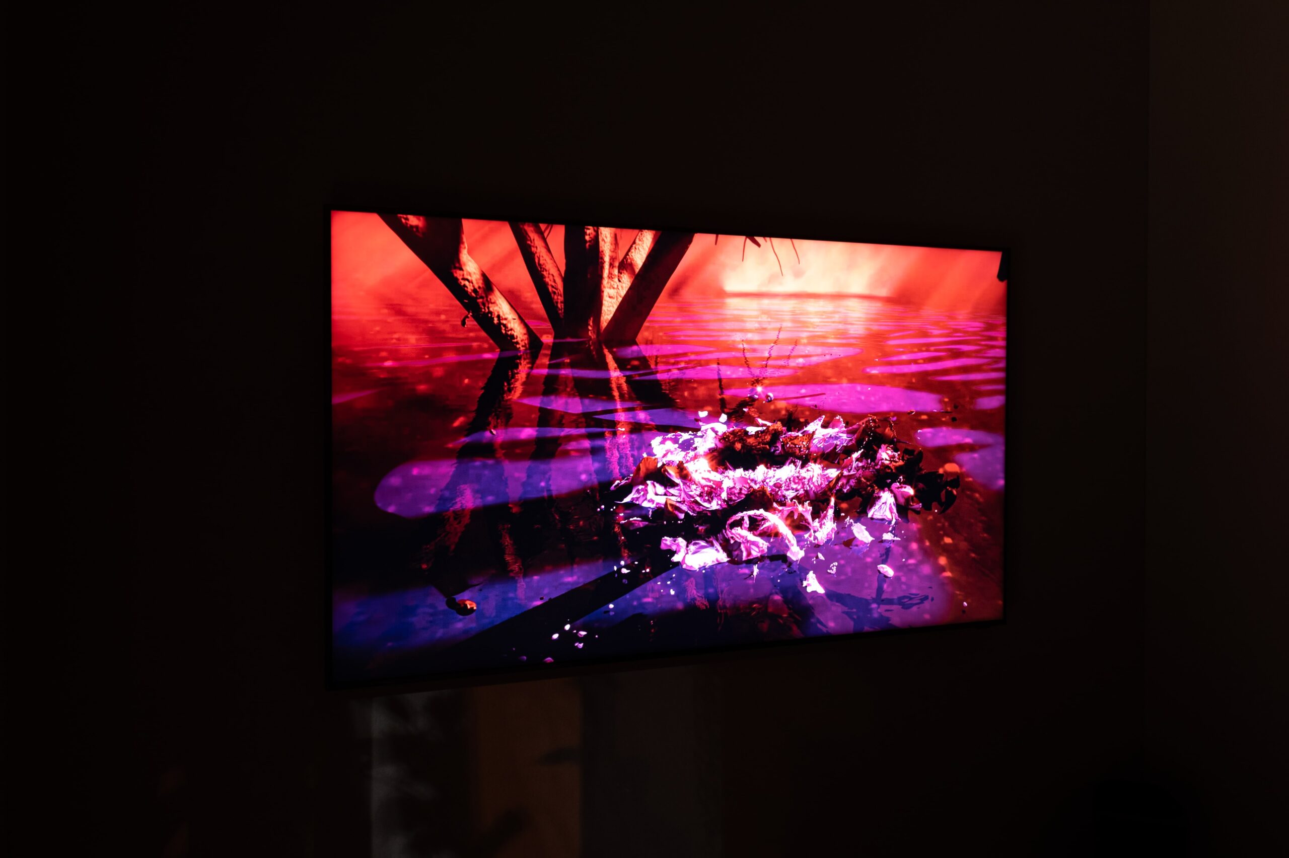 A photo of a projected semi-abstract image with red and purple colors in a pitch-black room