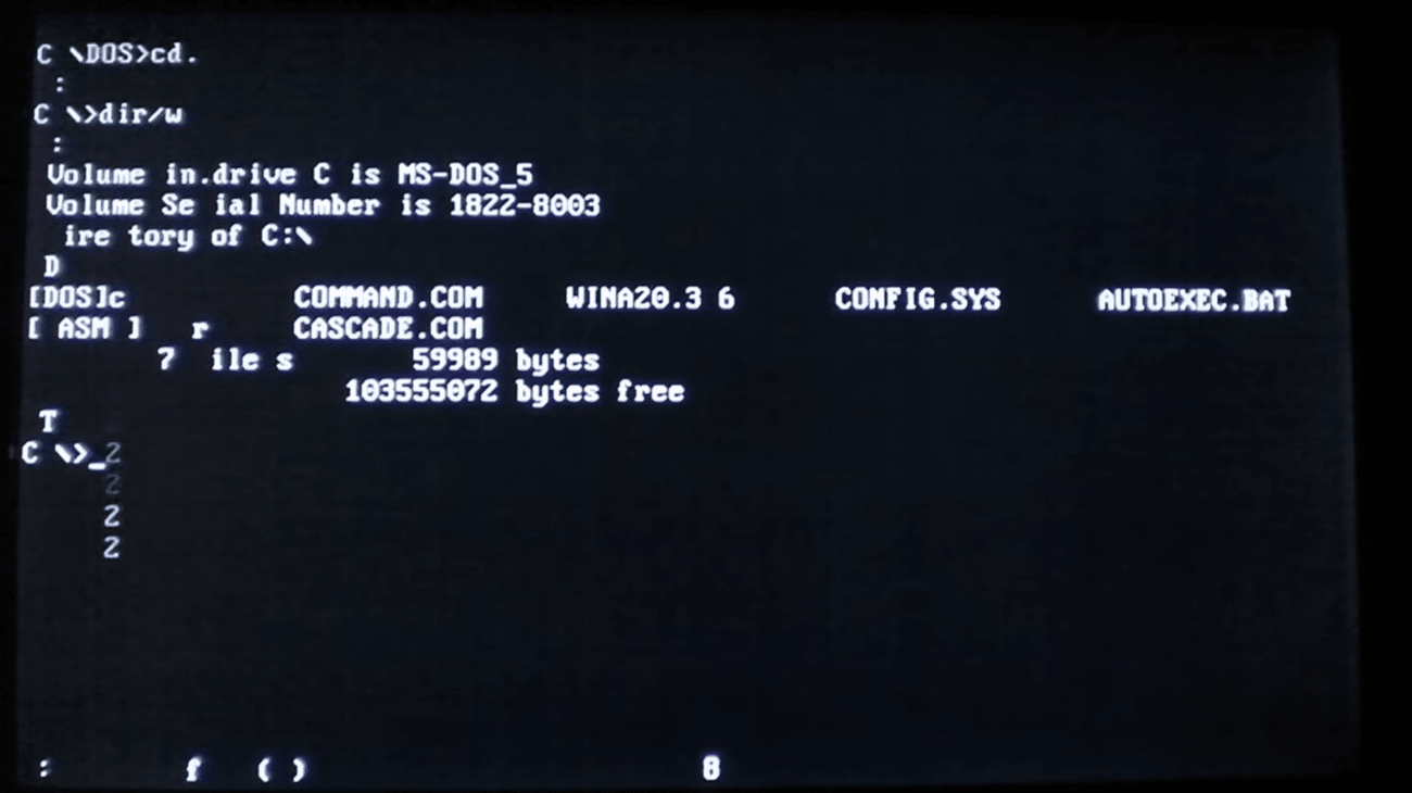 A shot of a black DOS screen where pale figures accumulate at the bottom in an incoherent jumble