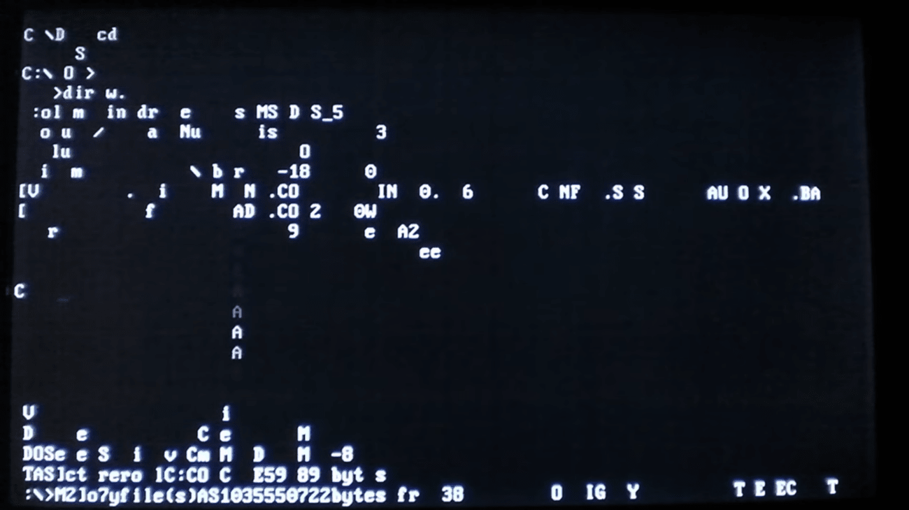 A shot of a black DOS screen where pale figures accumulate at the bottom in an incoherent jumble