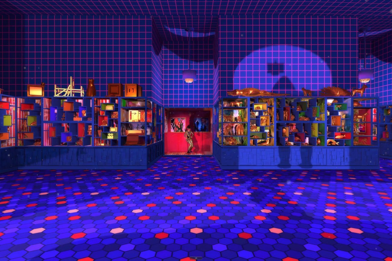 A view of a room coveredin dark blue tiles, hexagonal on the floor and square on the walls, with dramatically lit cabinets set in the walls holding numerous brightly colored objects