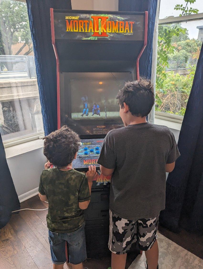 Two children play a vintage arcade game