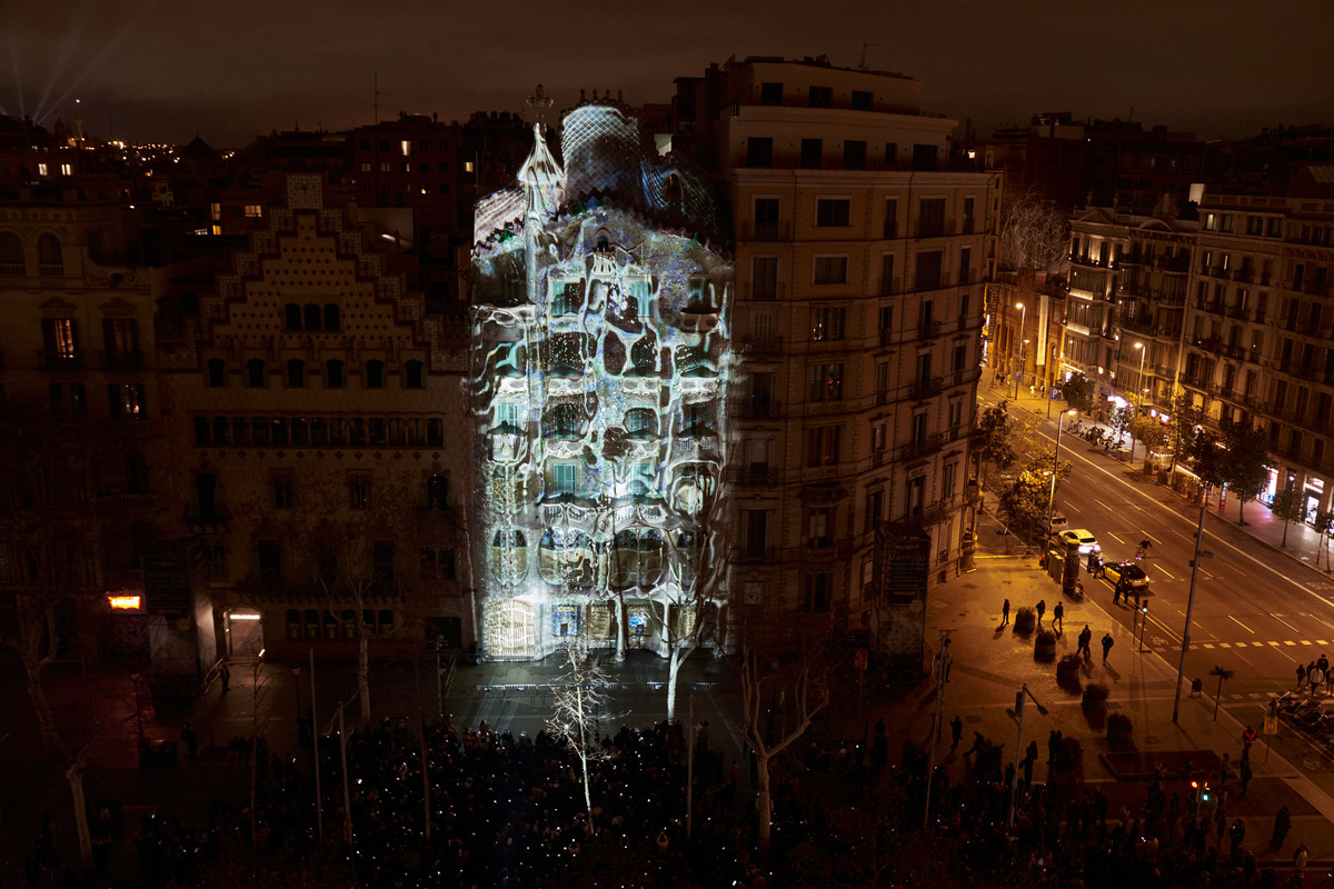 A night-time photo of a projection mapping on the facade of an apartment block, with closed roads visible in the background