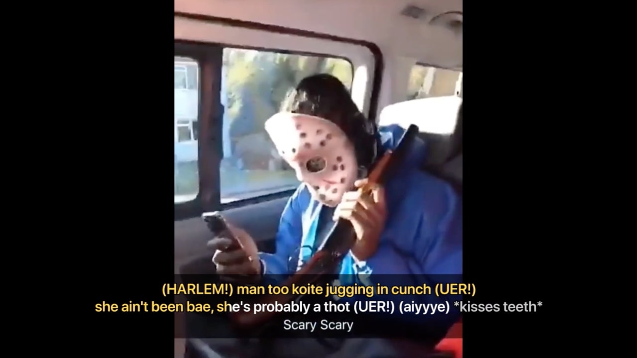 A still from a video showing a shaky image of a masked man with subtitles