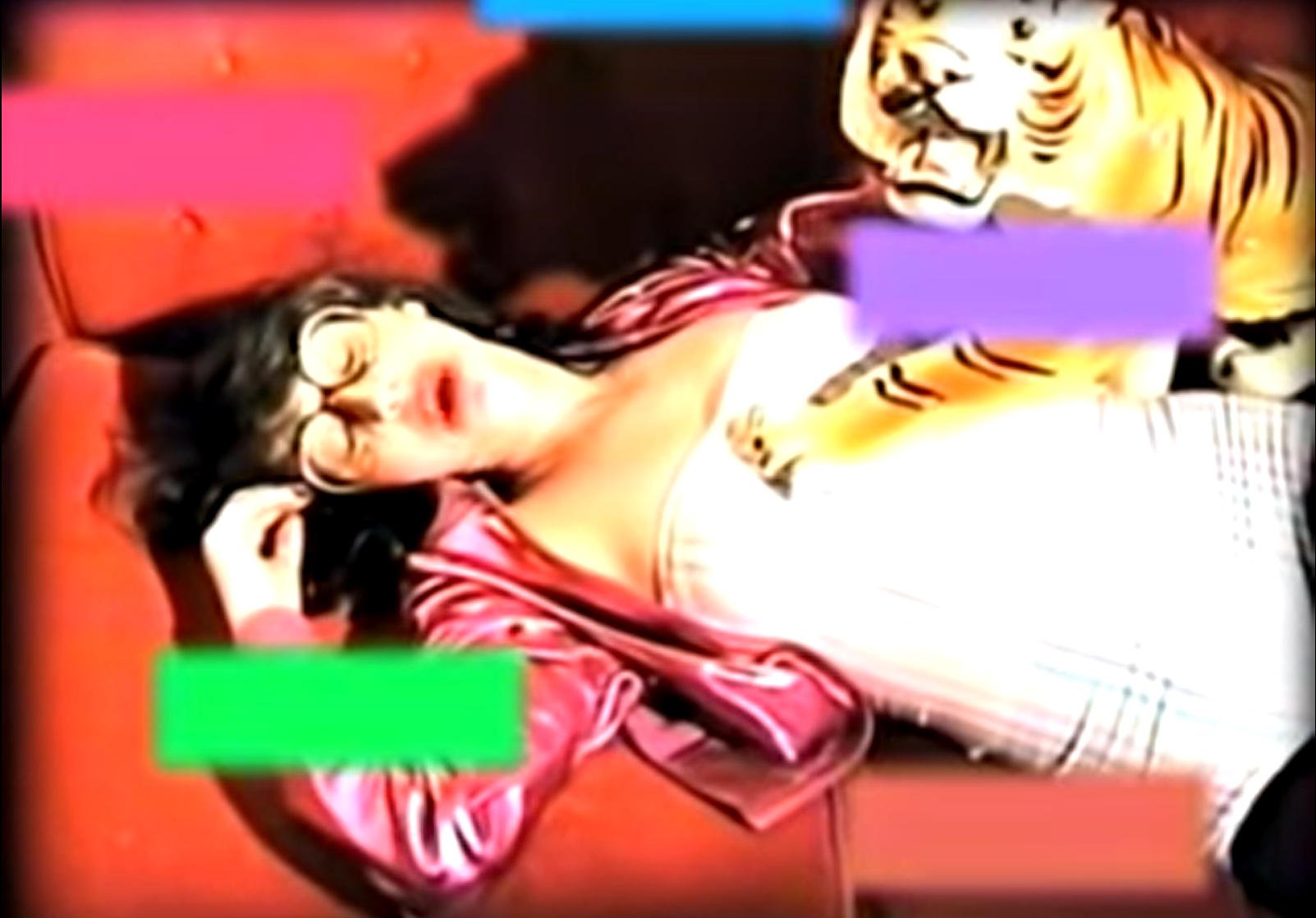 A still from a heavily edited video, where a young woman sings and writhes on her bed while strips of color float over her