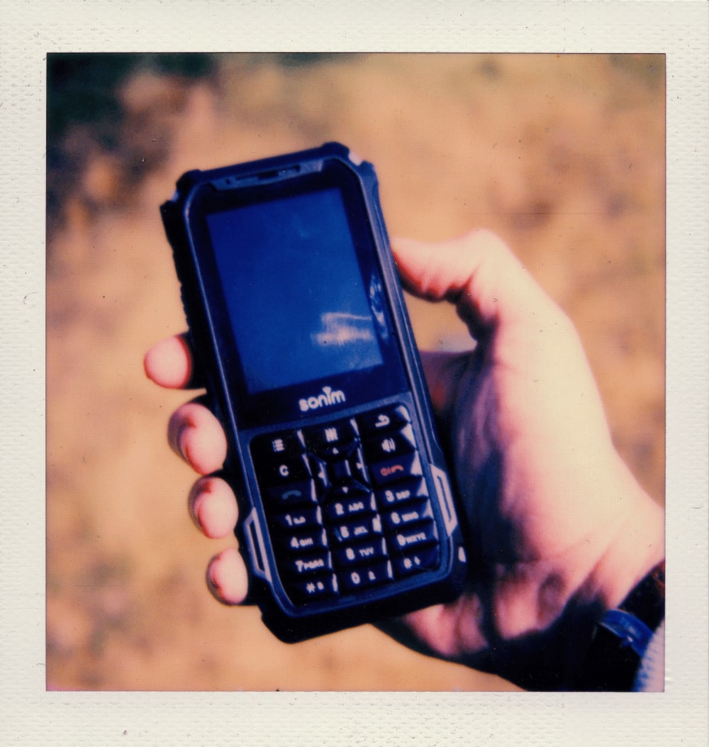 A polaroid photo of a brick phone held in somebody's palm