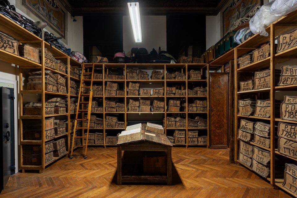 A photograph of a room whose shelves are piled with heavy old ledgers from the eighteenth century