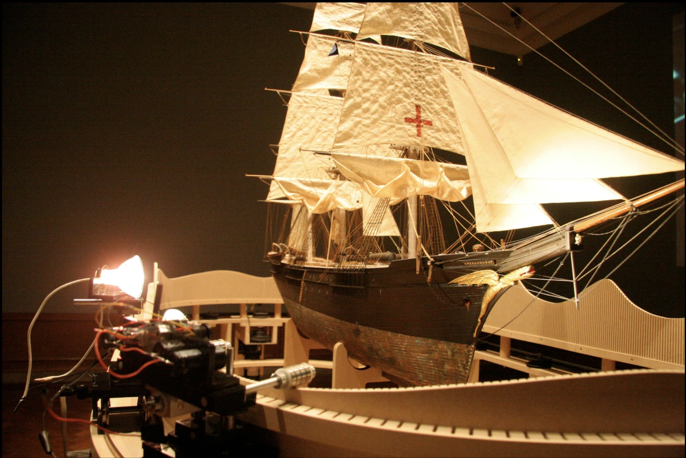 A photo of a sculptural installation featuring a model of a boat